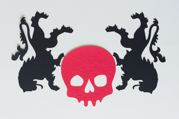 two upside down heraldic lions and red paper skull head