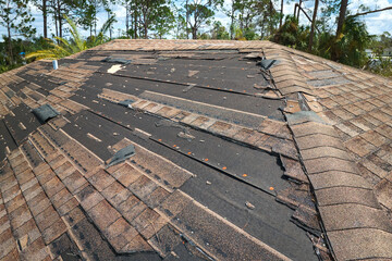 Damaged house roof with missing shingles after hurricane Ian in Florida. Consequences of natural disaster © bilanol