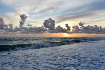 Beautiful sunset scene on a beach with sea, waves and clouds