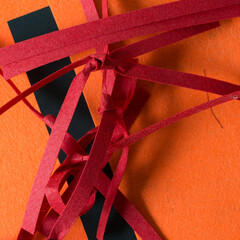 folded and or knotted felt stripes on orange fabric and black paper