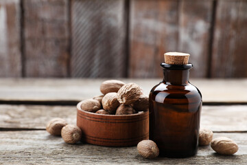 Obraz na płótnie Canvas Bottle of nutmeg oil and nuts on wooden table