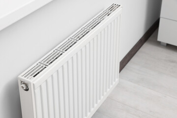 Modern radiator on white wall in room. Central heating system