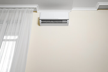 Modern air conditioner on white wall indoors