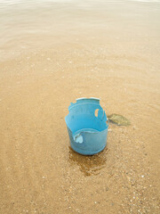 Broken blue plastic bucket on a sandy beach