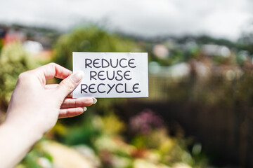 sustainability and circular economy, reduce reuse recycle sign in front of backyard bokeh