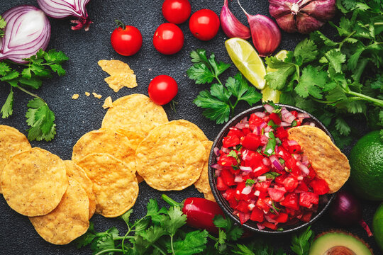 Mexican Food. Spicy Salsa Sauce With Tomatoes, Chili Peppers, Onion, Garlic And Cilantro With Nachos Corn Chips, Black Table Background, Top View