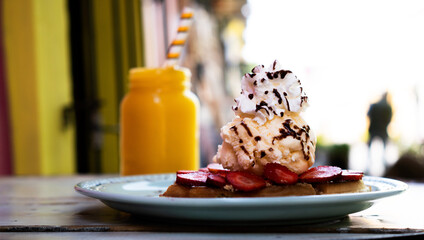 Waffles with ice cream on a plate on a wooden table in an open-air restaurant