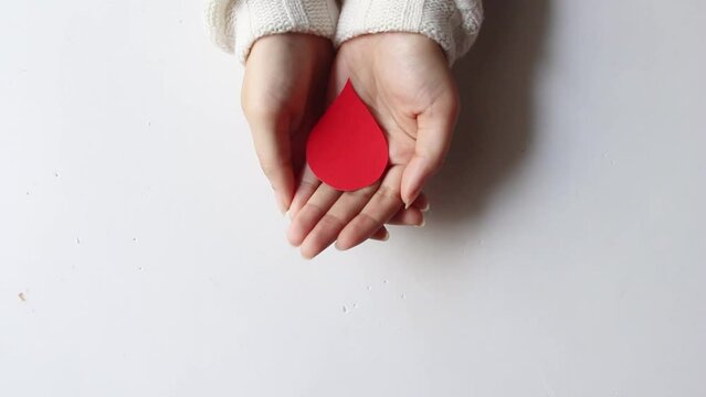 hand blood drop shape made from paper on white background, copy space, top view. blood donation concept, world blood donor day