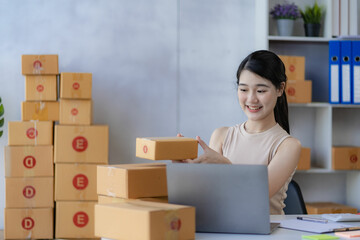 sme business idea cute asian woman selling online at home with laptop to take orders and to deliver yellow parcel boxes online delivery ideas