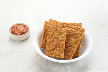 Tempeh, Tempe Goreng or Fried tempeh is Indonesia traditional food, made from fermented soybean seeds. Served with sambal (chilli sauce)