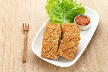 Tempeh, Tempe Goreng or Fried tempeh is Indonesia traditional food, made from fermented soybean seeds. Served with sambal (chilli sauce)