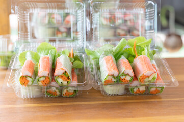 Salad rolls, made from vegetables and flour Small cup salad dressing Set up beautiful decorations on a black container as the background image.
