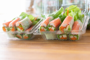Salad rolls, made from vegetables and flour Small cup salad dressing Set up beautiful decorations on a black container as the background image.