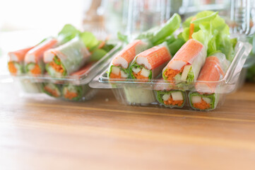 Salad rolls, made from vegetables and flour Small cup salad dressing Set up beautiful decorations on a black container as the background image.