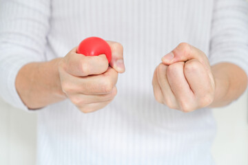 Hands of man with a gentle personality He exhibits stressful behavior from work, and he squeezes the yellow ball expressing emotion, anger, displeasure. Medical concepts and emotional regulation