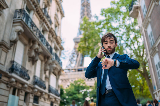 Holidays in Paris. Man in a suit using her smartphone in Paris, France. European worker. Street with Eiffel Tower view.