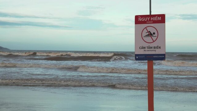 No Swimming Red Warning Sign on Beach in Front of Sea Waves Before Tropical Storm in Vietnam