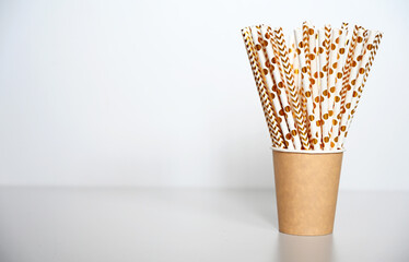 White gold straws in paper cups. Party concept.