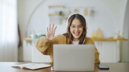 Young asian woman wearing glasses and headset working on computer laptop at house. Work at home, Video conference, Video call, Student learning online class