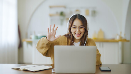 Young asian woman wearing glasses and headset working on computer laptop at house. Work at home,...