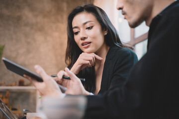 Two young business people work together in office. Concept of presentation new idea business project. Designer offers a job to a young businesswoman.