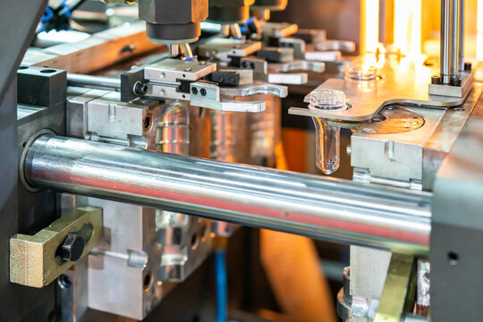 Plastic clear bottle preform hang on blowing gripper holder while open mold at automatic machine during manufacturing process in industrial