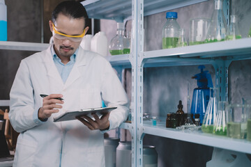 research man is standing and making notes on a pen in his notebook in a laboratory.