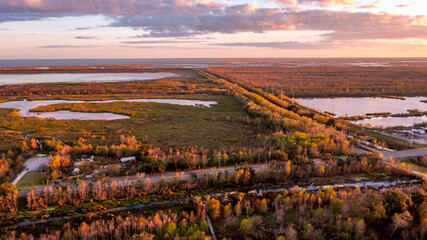 a long road in sunset over forests and a distant lake under cloudy sky 