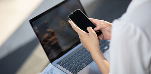 Mobile payment, female hand, focus on using smartphone and credit card and laptop for online...