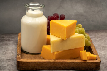 Cheddar cheese on a tray with grapes and bottle of milk