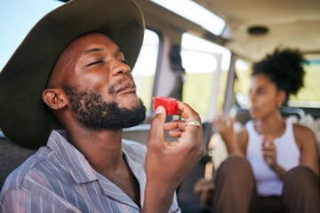 Black man, eating watermelon and summer fruit on safari game drive in sustainability nature or environment landscape travel. Smile, happy tourist or couple and diet health food in Kenya national park