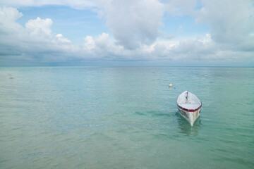 a lonely white wooden boat park in the beautiful clear tosca derawan beach