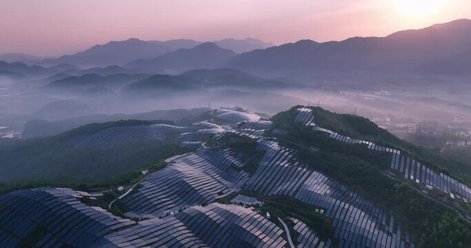 aerial view of solar power panels on hill at sunset