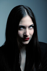 Fototapeta premium Beauty, make-up, horror and fashion concept. Sexy and beautiful woman with white eyes, red lips and long dark hair looking with uncomfortable and horrifying look. Toned image with blue color