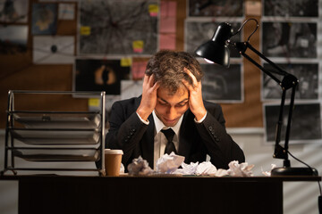 Serious frustrated detective with closed eyes suffering from migraine headache at workplace,...