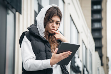 Fototapeta premium Business young woman with a tablet on the background of the building.