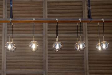 Globe glass pendant light Chandelier in Antique Brass Finish with wooden cladding background, selective focus, front view