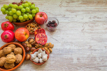 Fototapeta na wymiar Autumn fruit background. Autumnal fruit table. Grapes, figs, blackberries, passion fruit, pomegranate and delicious dried fruits. Image with copy space
