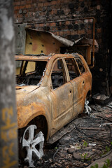 Broken and burnt car near the burnt house in Irpin after Russian invasion of Ukraine in spring
