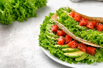 Sandwich with salmon, avocado, lettuce, sesame seeds. Flatbread, Healthy Tortilla, pita on grey background. Simple snack.