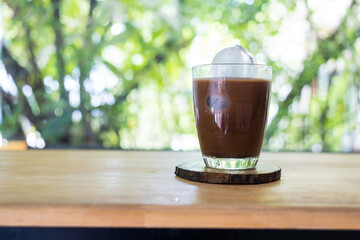 Iced Mocha coffee in a transparent glass on wooden saucer with homemade ice