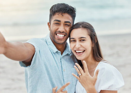 Couple selfie, engagement proposal or wedding ring at the beach, jewelry or engaged announcement. Romance face portrait, love and commitment of man and woman by the ocean celebrating with a smile.