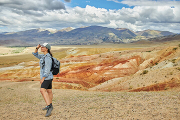 Fototapeta premium woman tourist in jeans jacket stands against backdrop of landscape on summer day. Sights of Russia, Siberia and Altai Republic, mars field. Tourism, travel and adventure. Kosh-agach, Chagan-Uzun