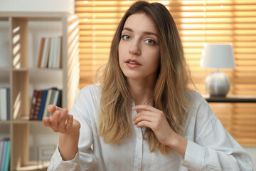 Young woman holding online webinar indoors, view from webcam