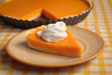 Piece of fresh homemade pumpkin pie with whipped cream on table