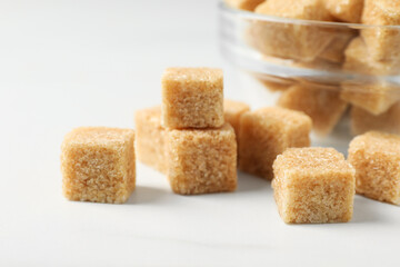 Brown sugar cubes on white table, closeup