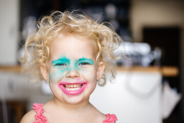 happy child applied makeup on his face by himself. Funny expression of emotion with a painted face...