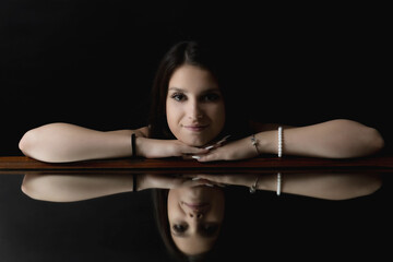 Low key portrait of brunette young woman  lying on the mirror. Horizontally. 