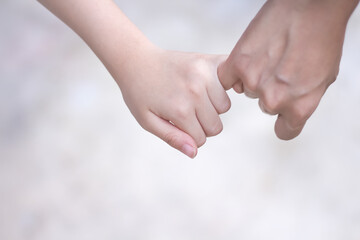 Asian child girl hand holding mother hand making a pinkie promise on background