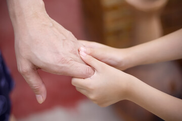 Blurred soft focus asian child girl hand holding father for familly bonding love background close up